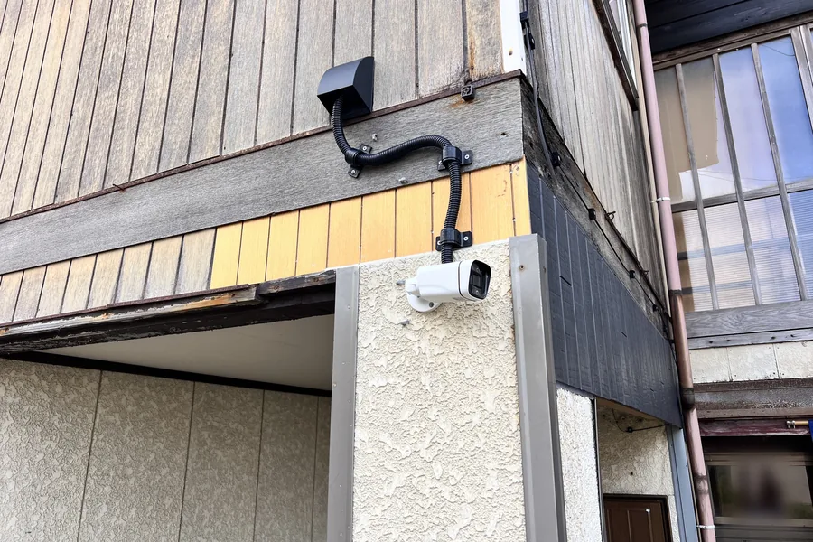 建物の角に設置した防犯カメラと、保護管で処理された配線
