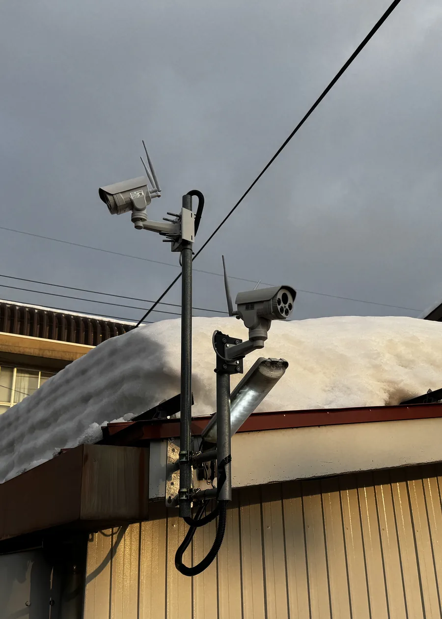 雪が積もった新潟の建物の軒先に設置されたワイヤレス防犯カメラ2台